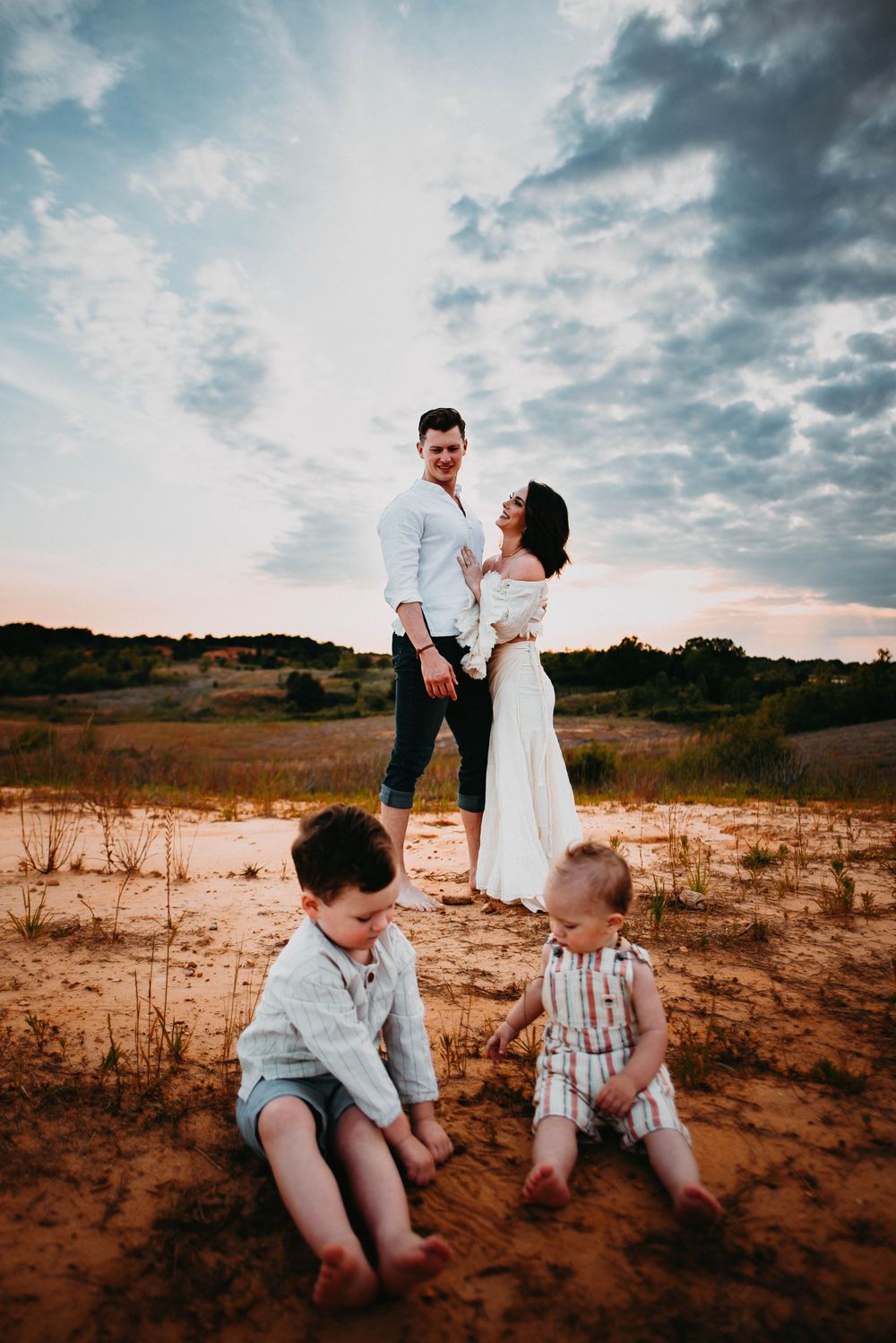 Family spending quality time together on sandy terrain during sunset.