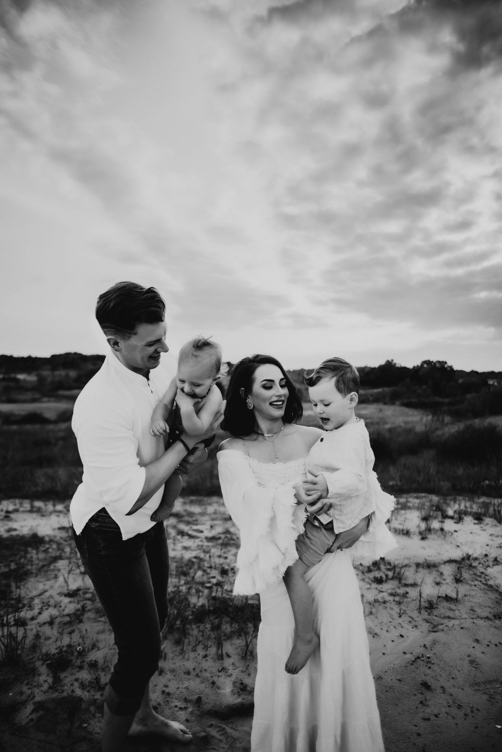 Black and white photo of family sharing joyful moments outdoors.