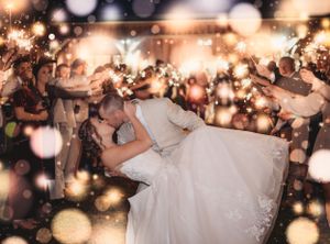 Wedding reception dance floor filled with guests under twinkling lights and bokeh effects.