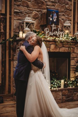 Wedding couple's first dance in rustic stone venue with twinkle lights and wooden beams.