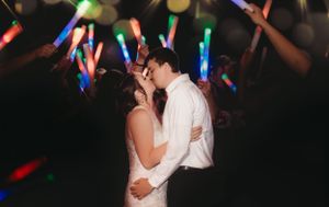 A romantic dance moment under colorful LED light wands at a wedding reception.