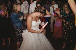 Wedding reception dance floor filled with guests celebrating under ambient lighting.