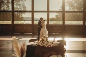 A romantic silhouette dance moment in a sunlit rustic venue with pampas grass decor.