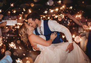 A couple sharing a romantic dip during their wedding dance surrounded by sparklers.