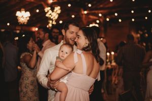 Couples slow dancing at an evening wedding reception under warm glowing lights.