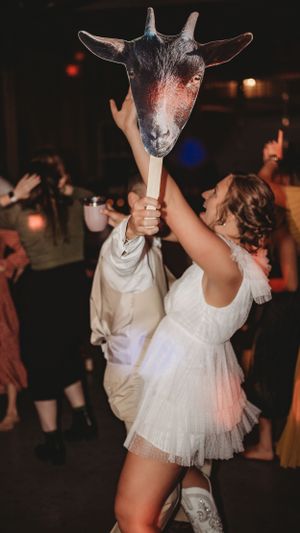 Wedding party dancing with goat head masks at nighttime reception.