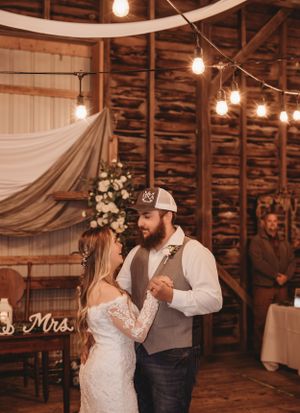 A romantic dance in a rustic barn venue decorated with string lights and white drapery.