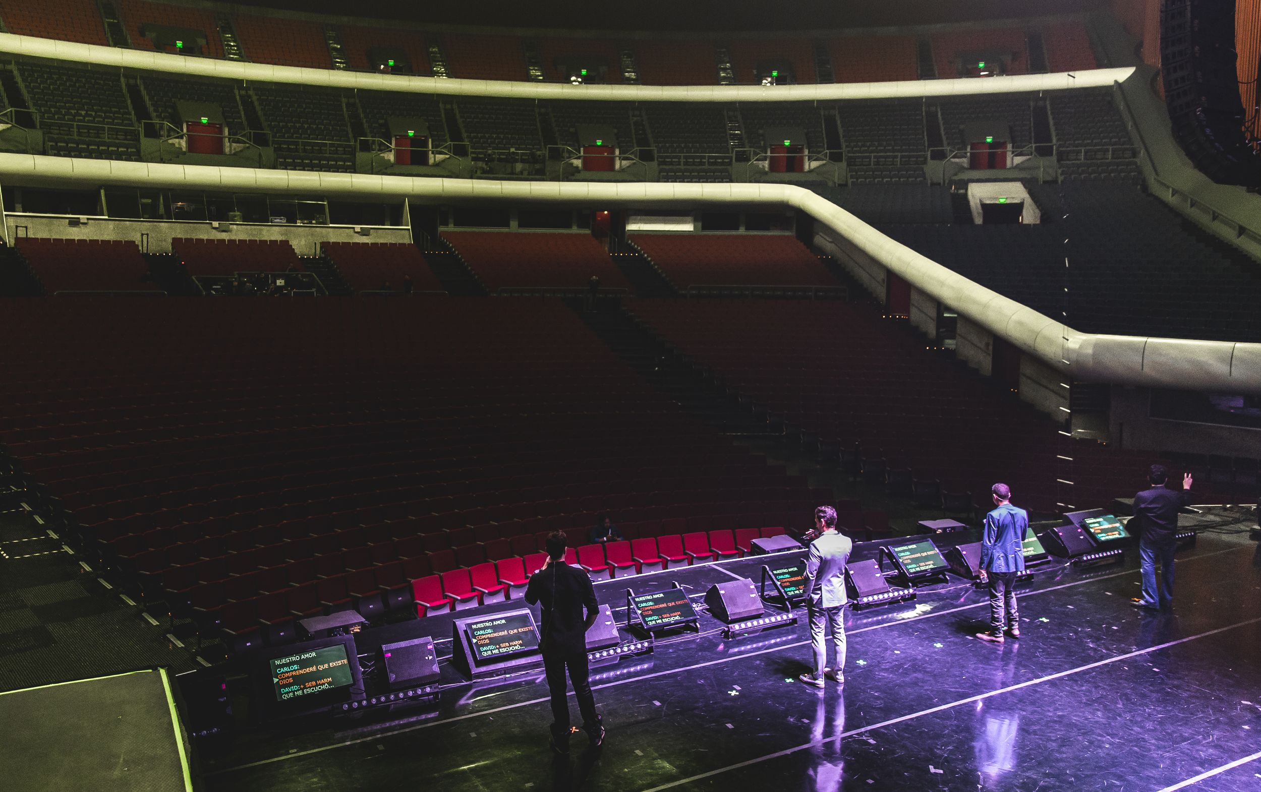 Wide concert hall view showing stage setup with dramatic lighting and seating arrangement.