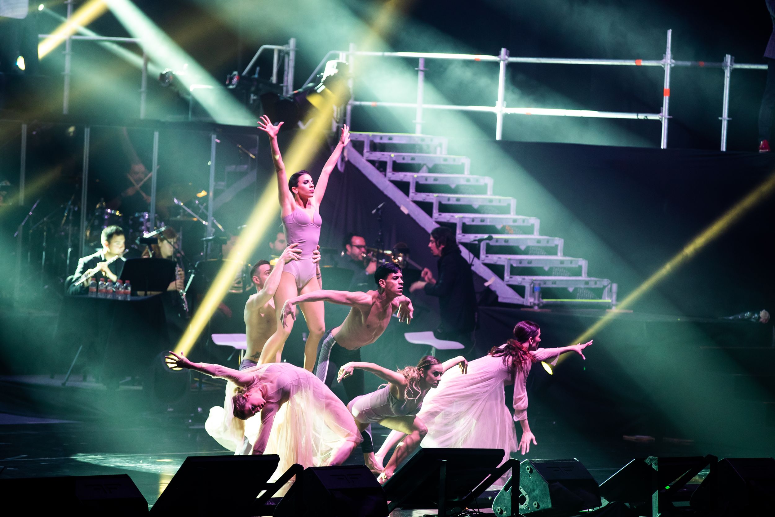 Large stage production with green lighting and dynamic visual effects during live show.