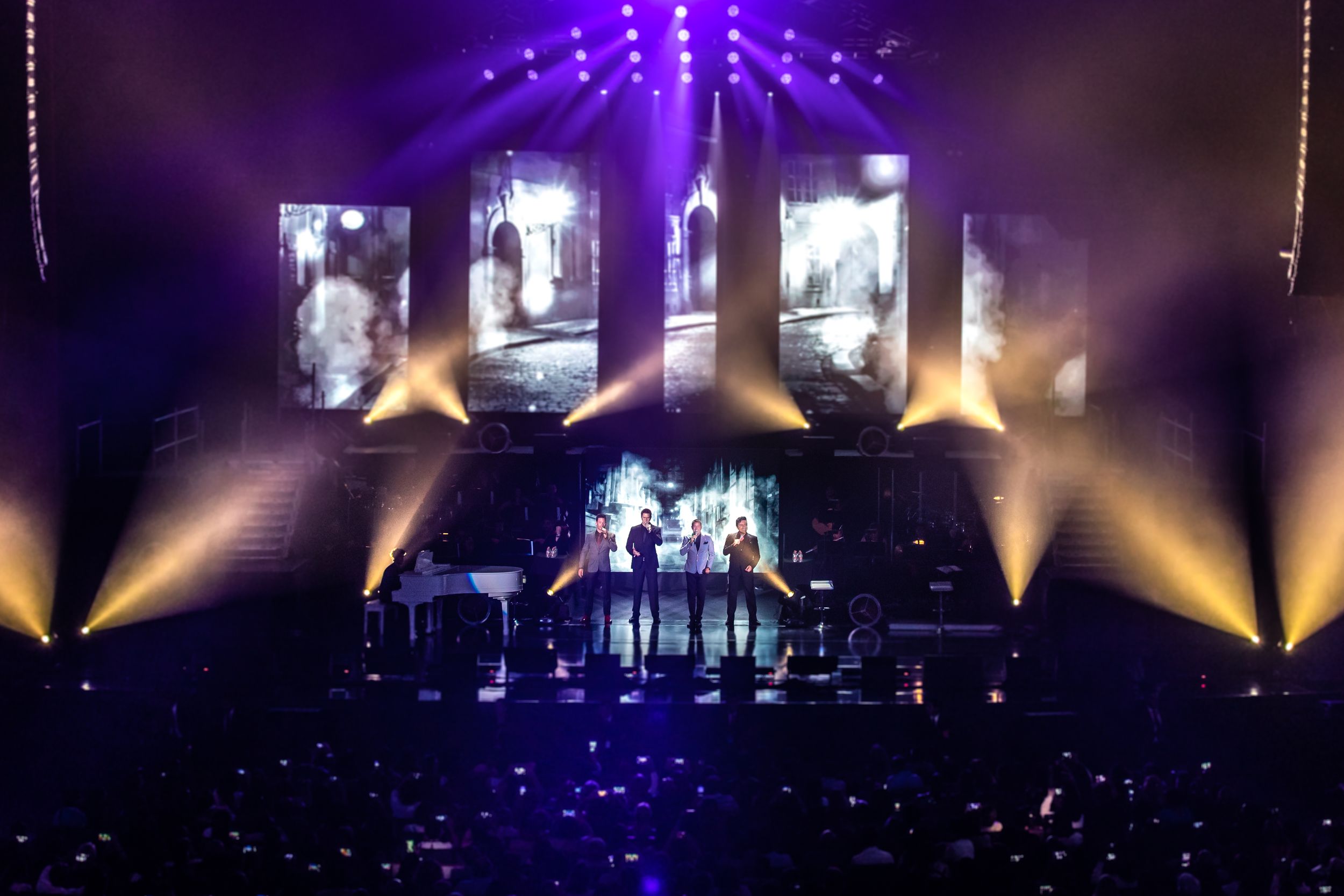 Concert stage lit with purple and gold lights creating dramatic atmosphere for performance.
