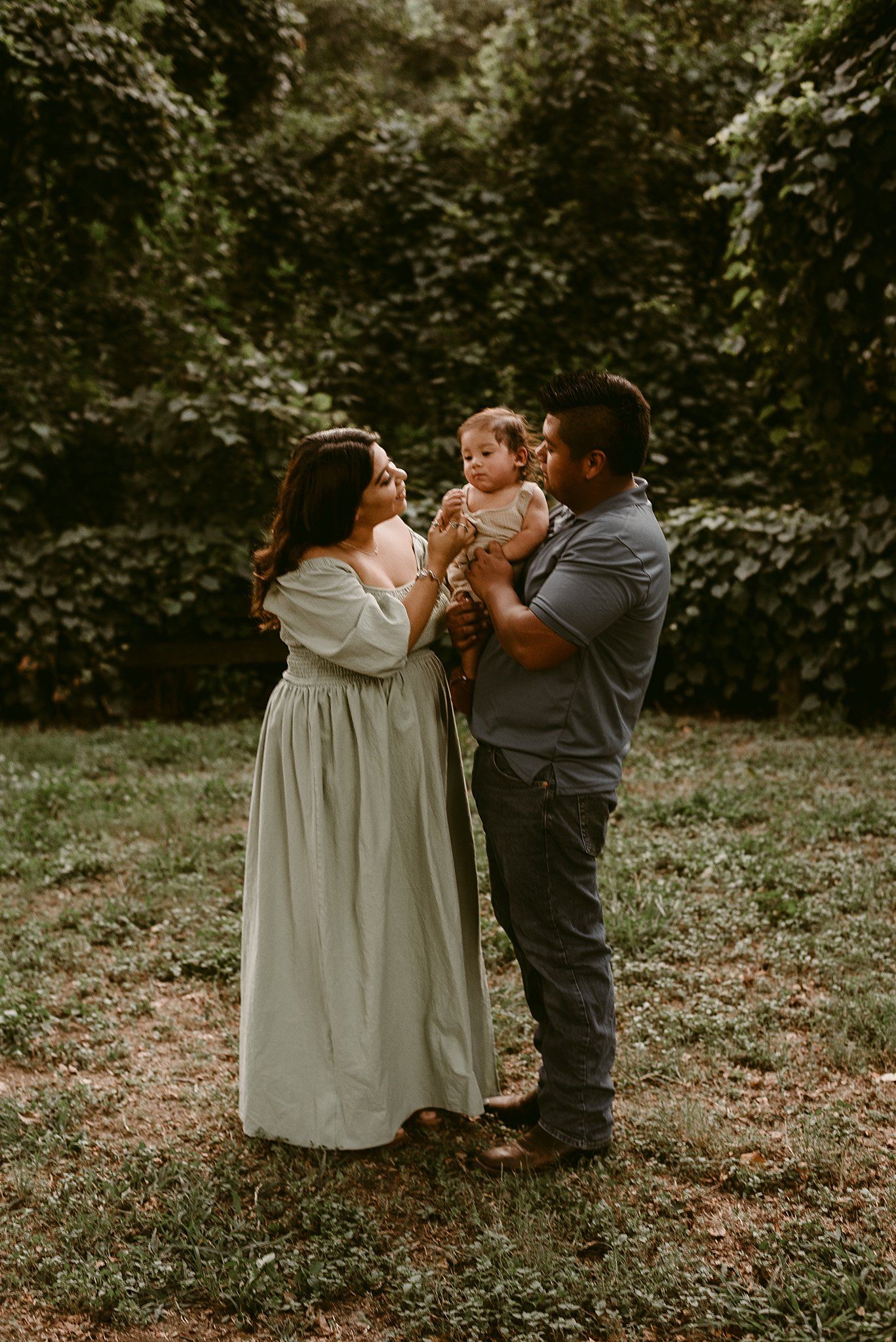 Family sharing tender moment together in garden with ivy covered wall backdrop.