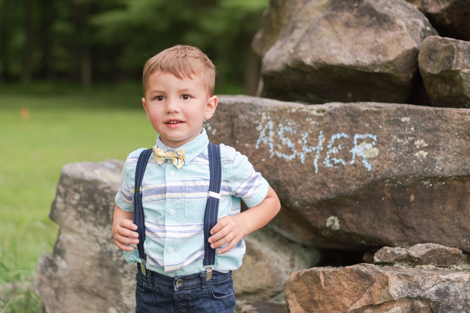 Little boy in suspenders standing in front of rocks in Clarion Pennsylvania