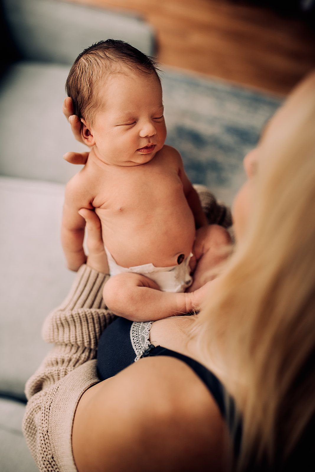 A view over a mother's shoulder while she looks down at her sleeping baby.