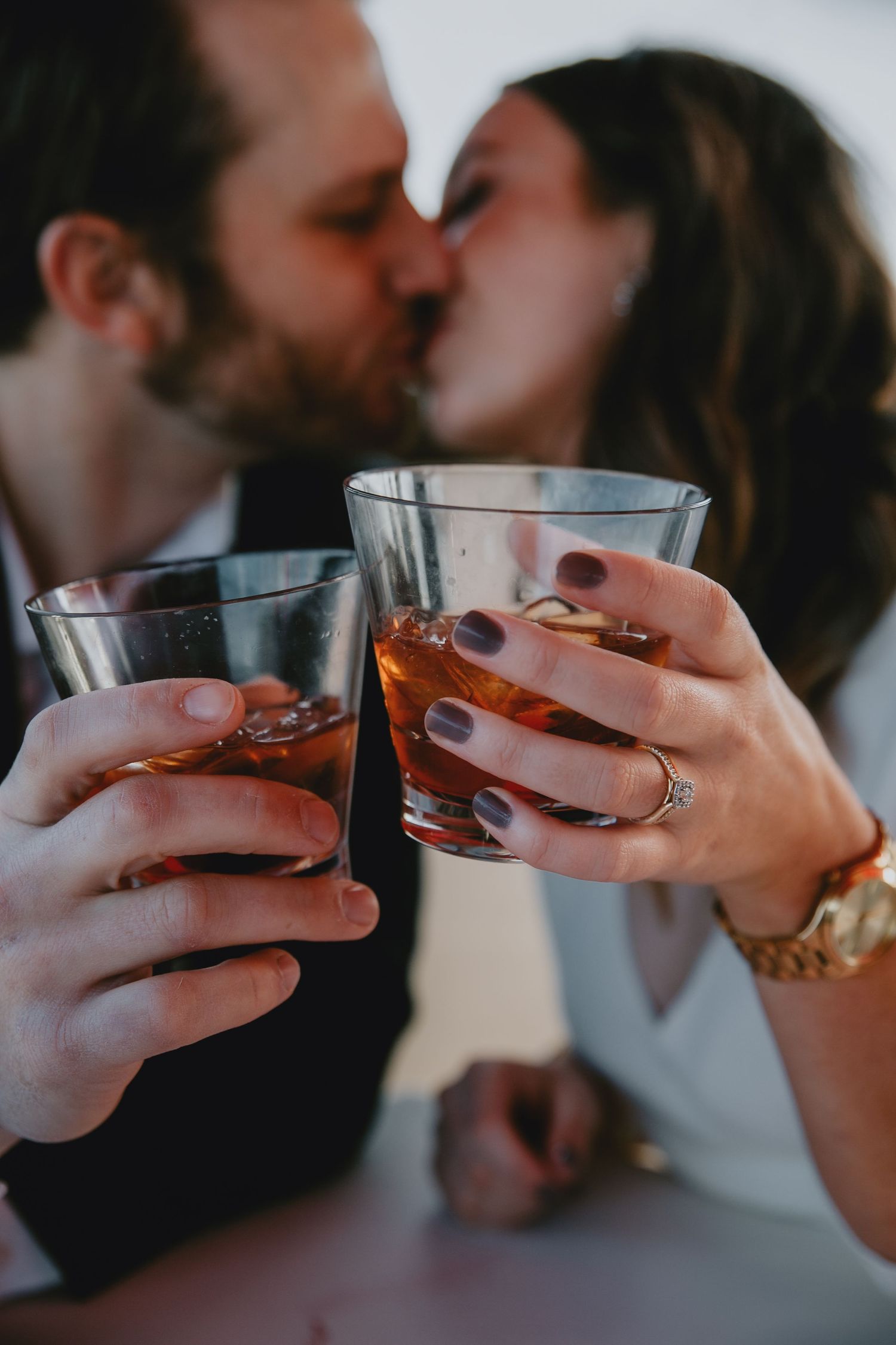 A man a woman cheers their drinks while kissing