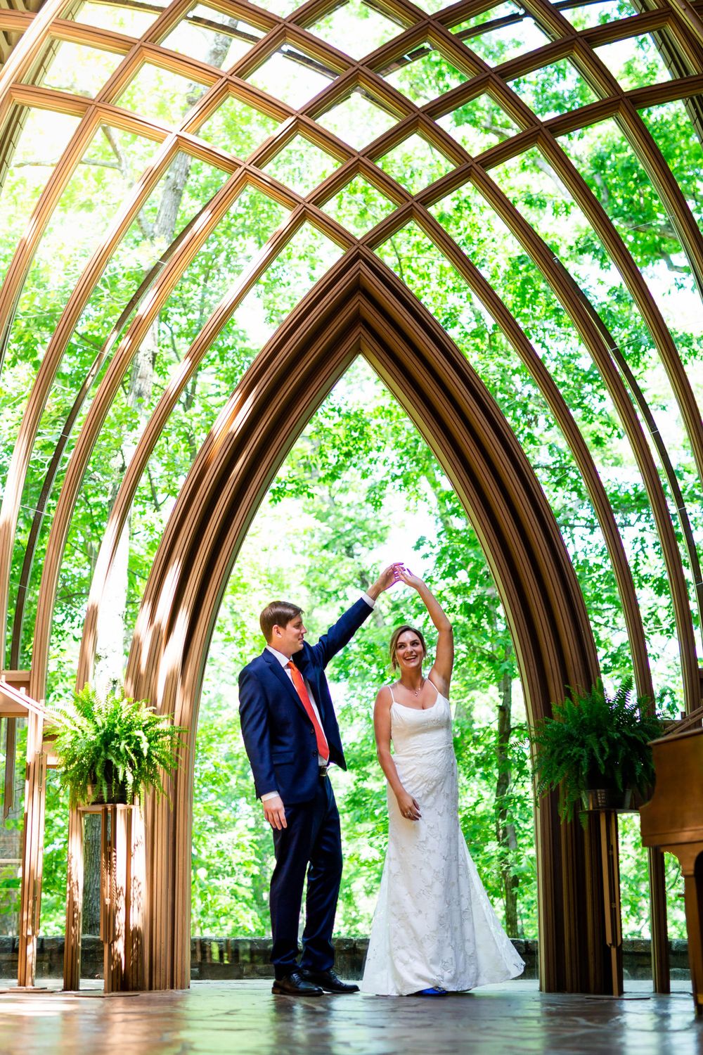 Newlyweds sharing a joyful dance under the stunning arches of Mildred B. Cooper Memorial Chapel in Bella Vista, Arkansas