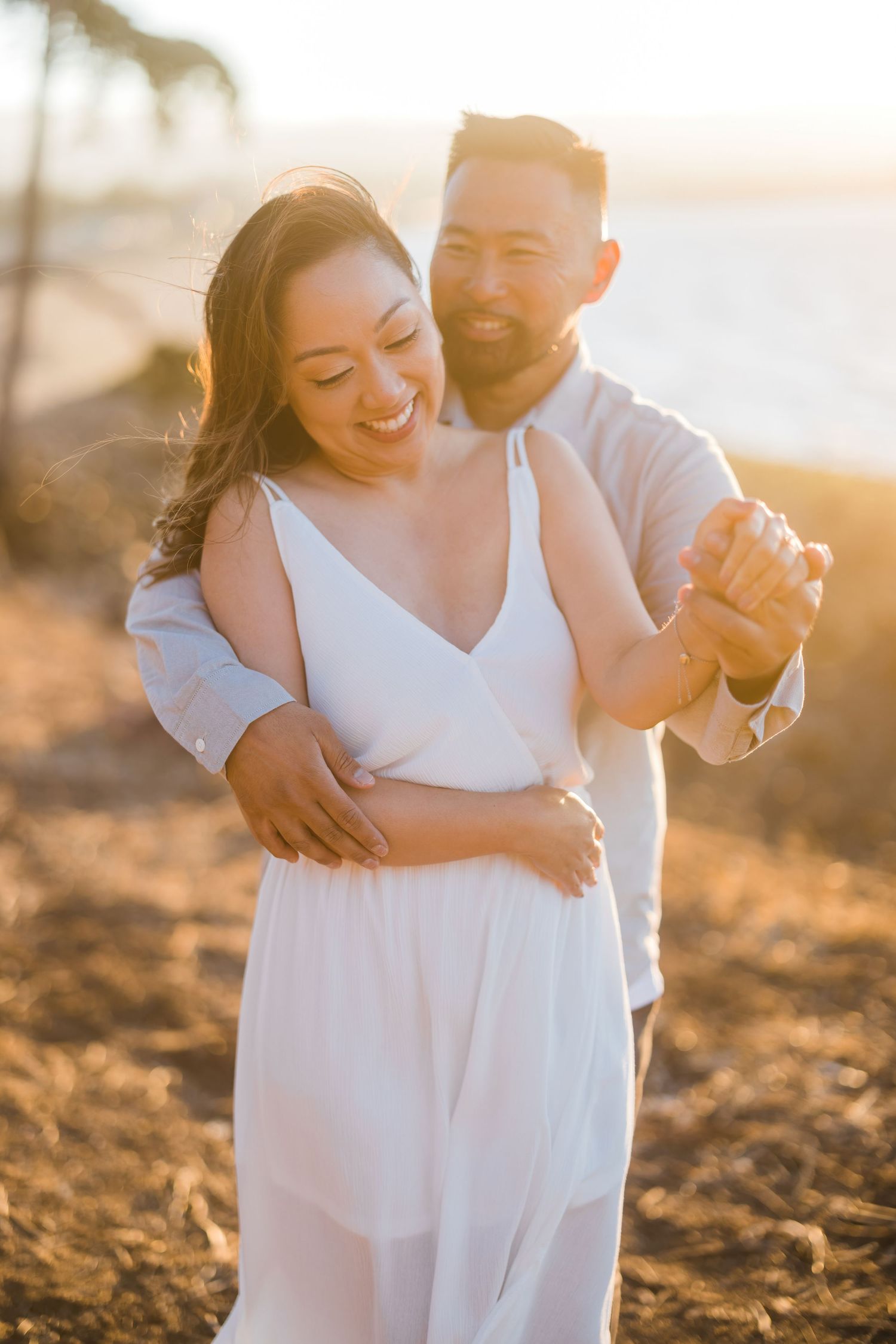 A couple shares a romantic moment during golden hour on a beach.