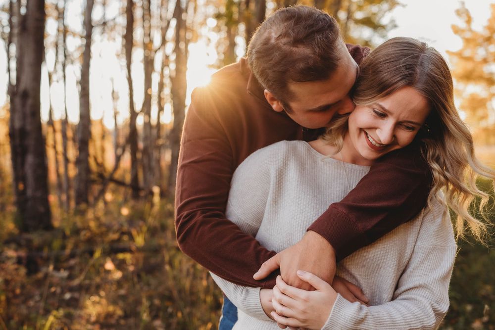 A romantic autumn photoshoot in a forest with golden sunlight filtering through trees.