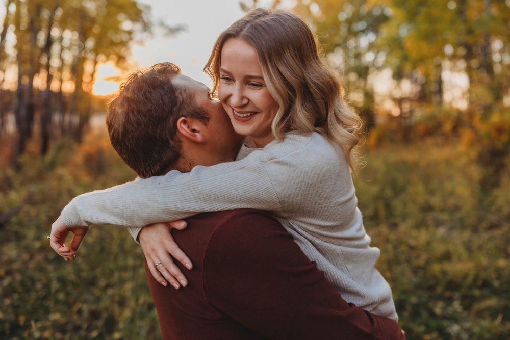 An intimate embrace captured during golden hour in an autumn forest setting.