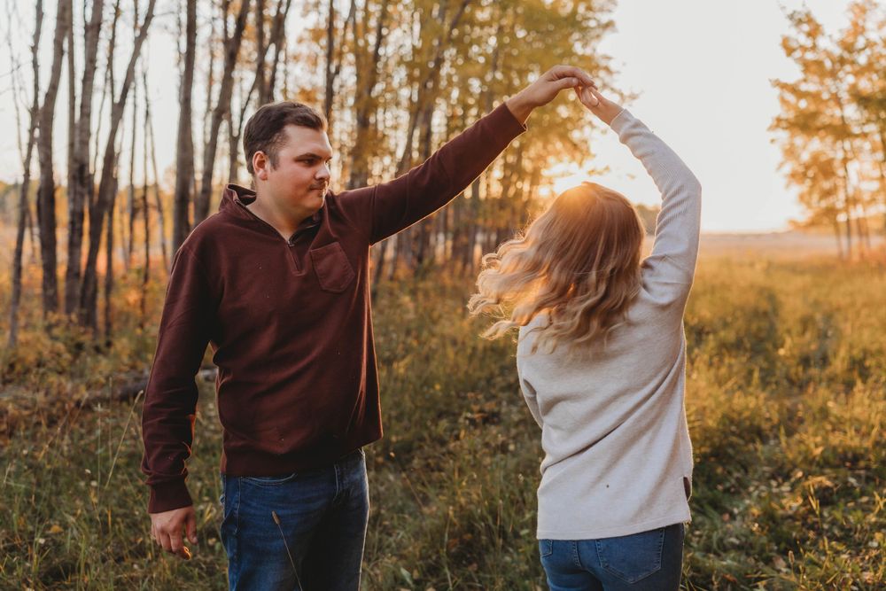 A playful dance moment captured during sunset in a rustic outdoor setting.