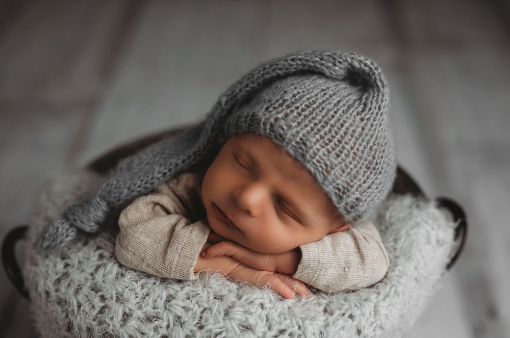 Newborn baby boy sleeping in bucket with sleepy cap on