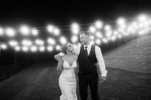 A couple shares an intimate moment under string lights outdoors during their wedding reception.