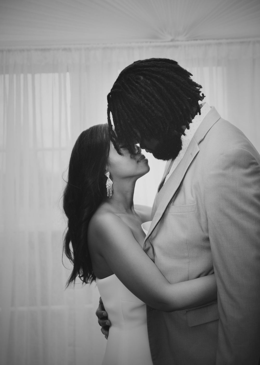 A black and white romantic portrait of a couple embracing in an intimate moment.