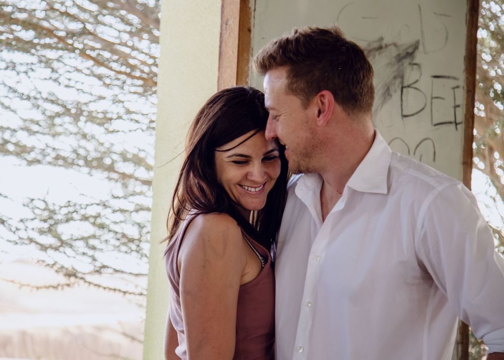 Candid romantic moment captured between a couple against a bright outdoor background.