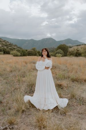 A dreamy white gown photographed against mountains and dry grassland.