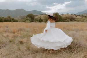 A white dress spins dramatically in a mountain field during golden hour.