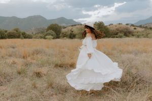 A flowing white dress twirls in motion against a mountain landscape.