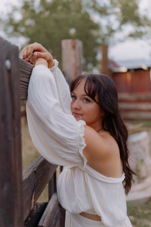 Flowing white fabric creates movement against a rustic wooden backdrop.
