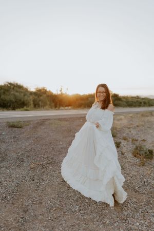 A flowing white dress twirls gracefully against a desert landscape at golden hour.