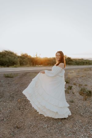 Ethereal white gown billows in the wind against a desert backdrop at dusk.
