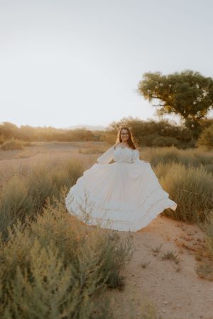 Romantic white dress spins against desert flora during sunset.