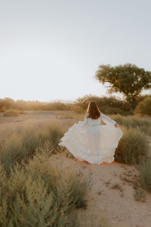Whimsical white dress movement captured in desert setting at dusk.