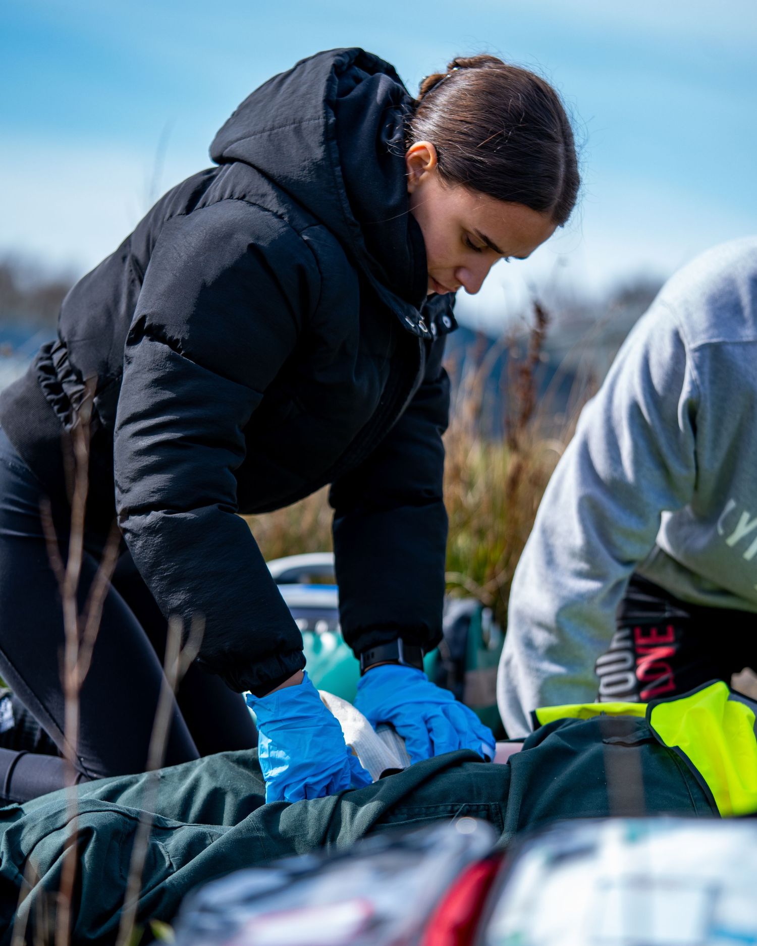 Medical professional provides emergency care during outdoor training exercise.