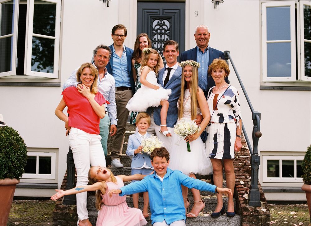 A group photo on the steps of a white building during a special occasion.