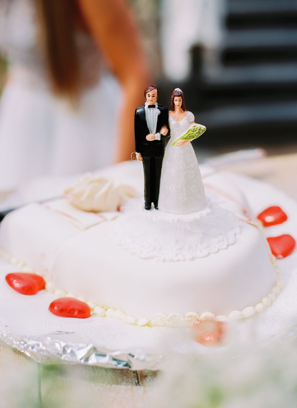 A classic bride and groom cake topper decorates a white wedding cake with pink accents.