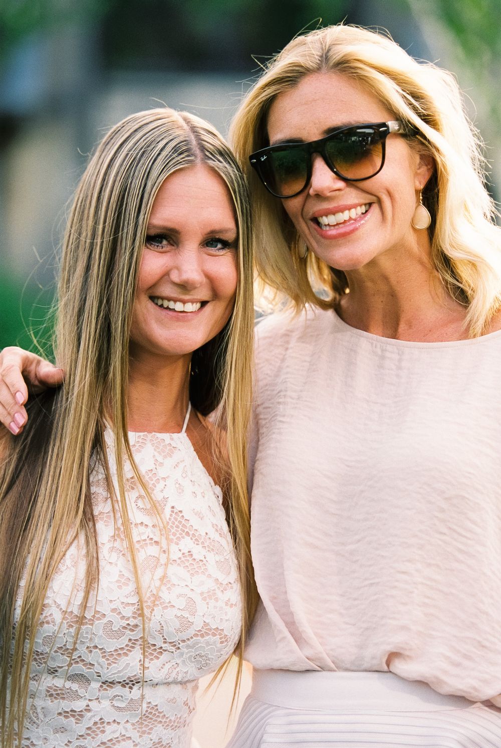 Two close friends pose together, one in white lace and one in a light colored top.