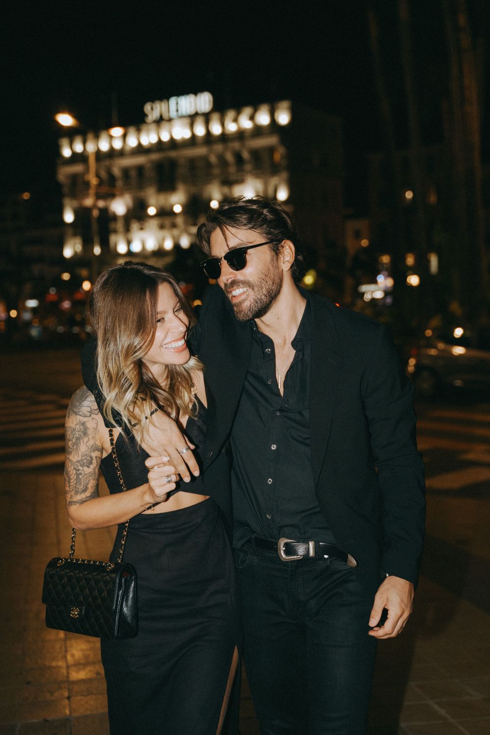 Couple sharing intimate moment while walking through city streets at night.