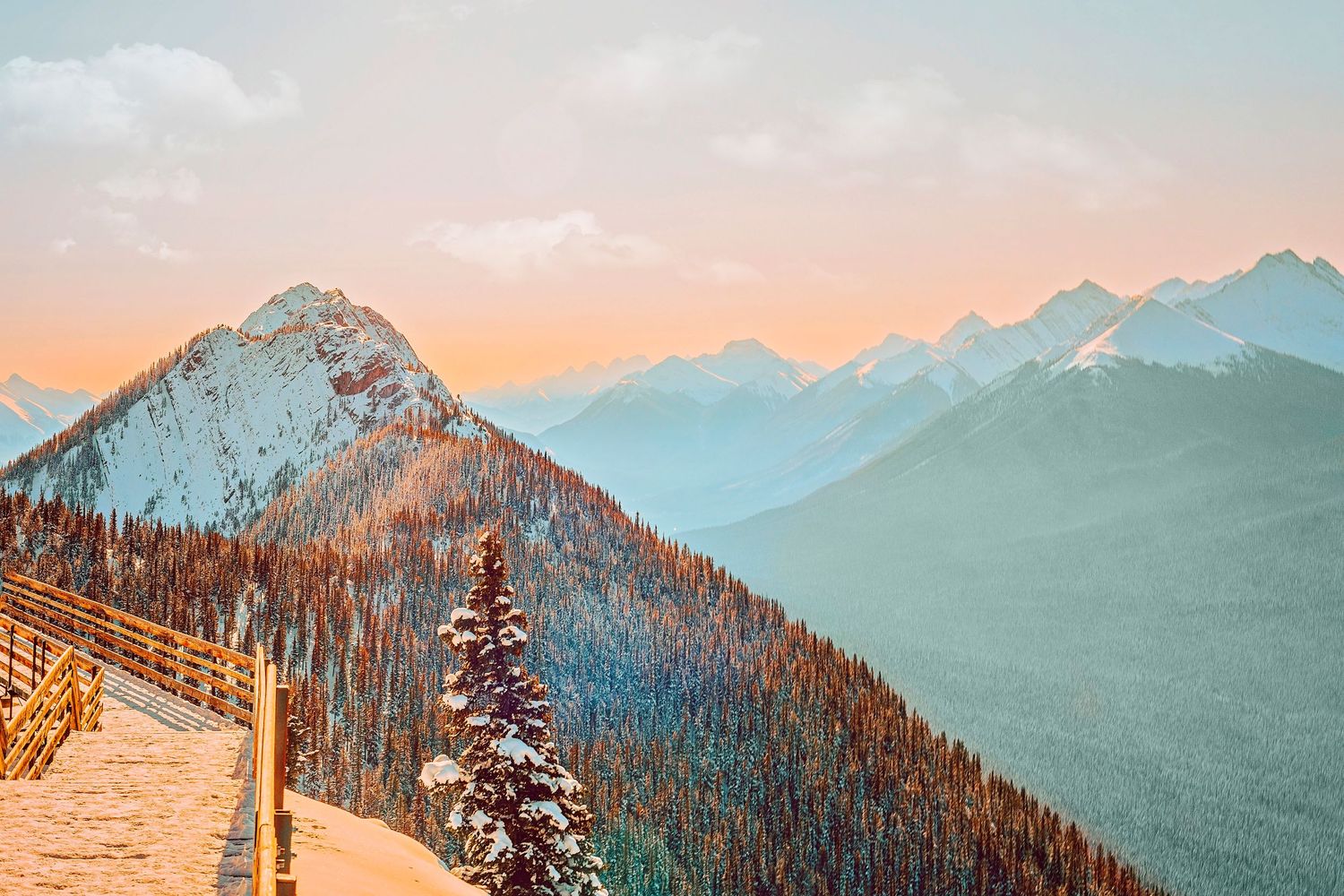 Snowy mountain peaks at sunset with orange sky in winter landscape.