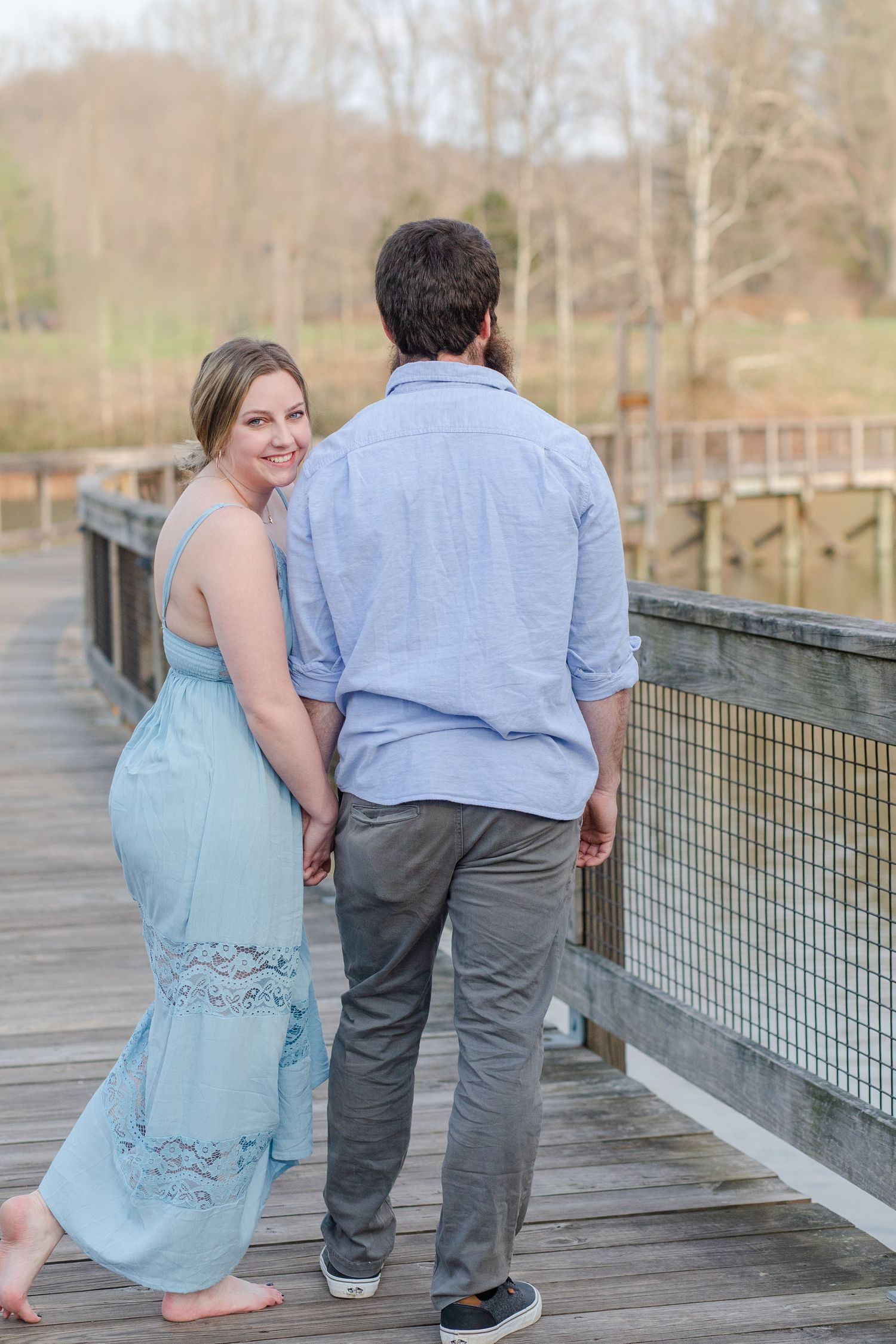 A couple walking hand in hand along a wooden boardwalk on a sunny afternoon.