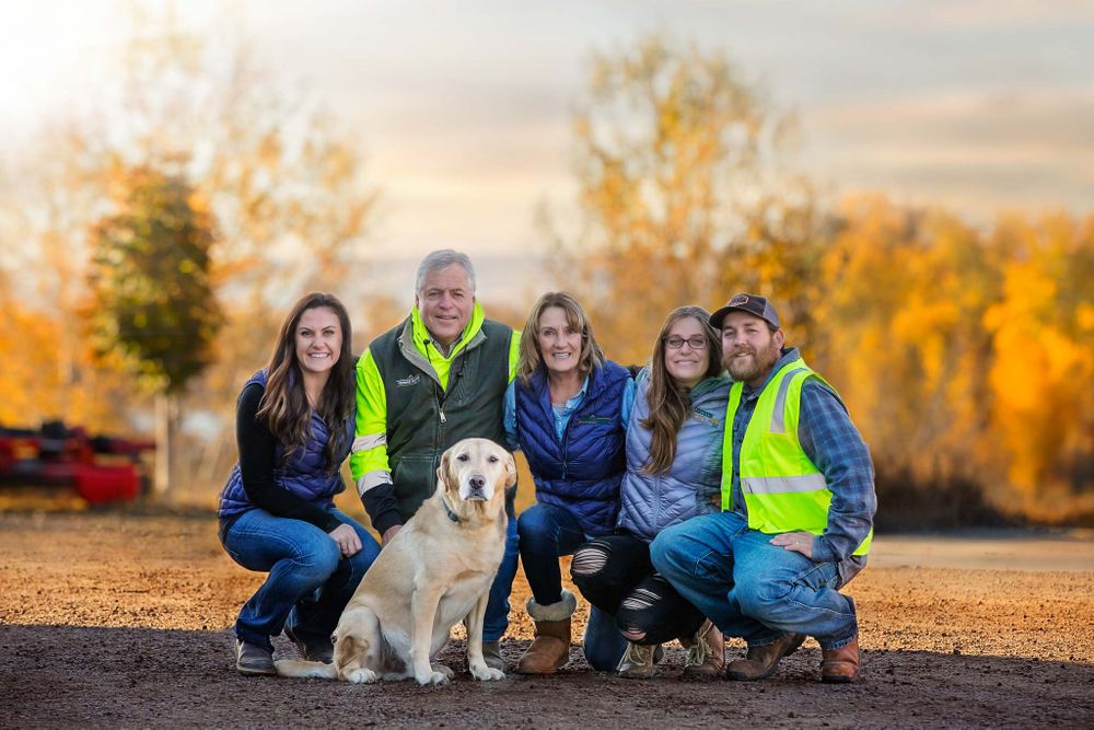 Business owners and family crouching around family dog in fall foliage