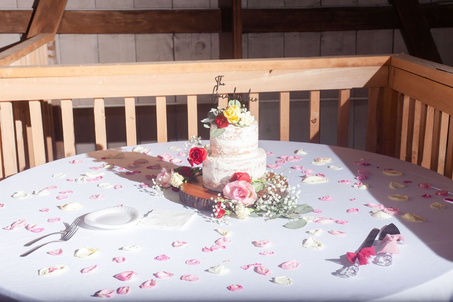 A wedding cake display table decorated with scattered flower petals.