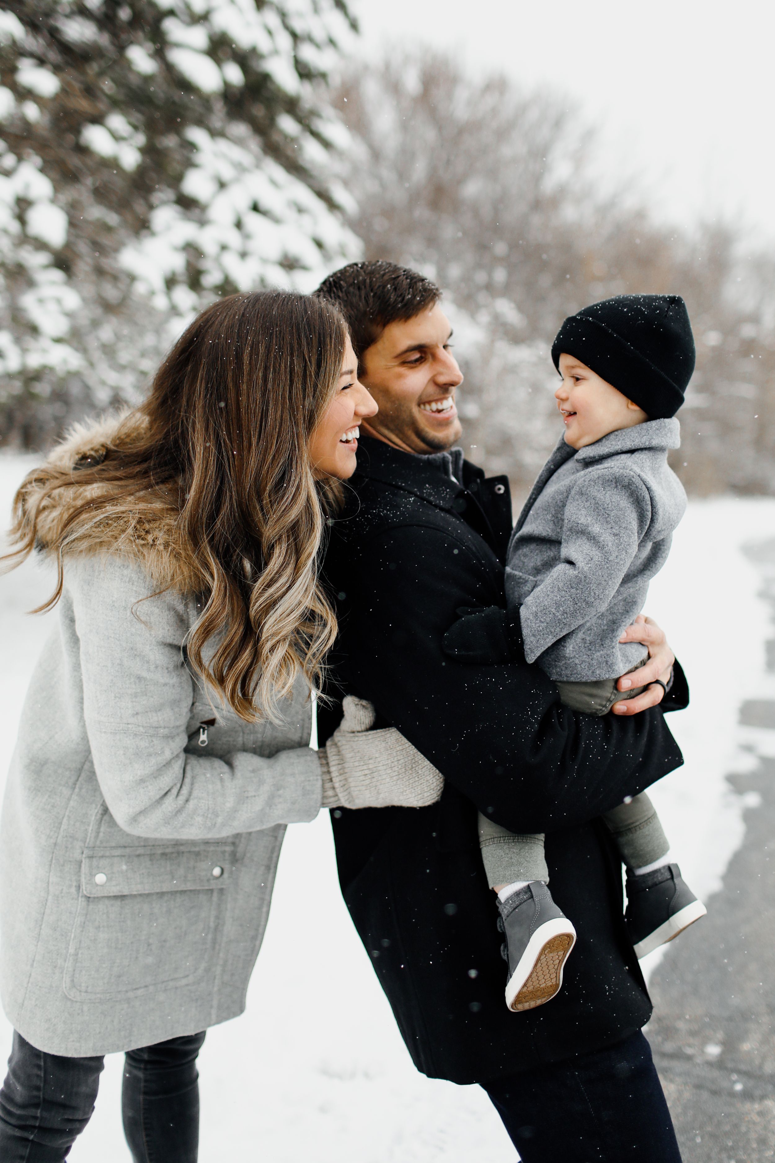 Winter portrait series of a couple playing in the snow wearing cozy coats.