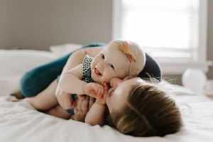 Baby lying peacefully on white bedding in natural light.