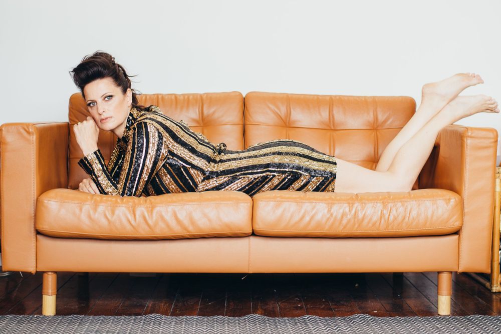Person lounging on tan leather couch wearing striped gold outfit.