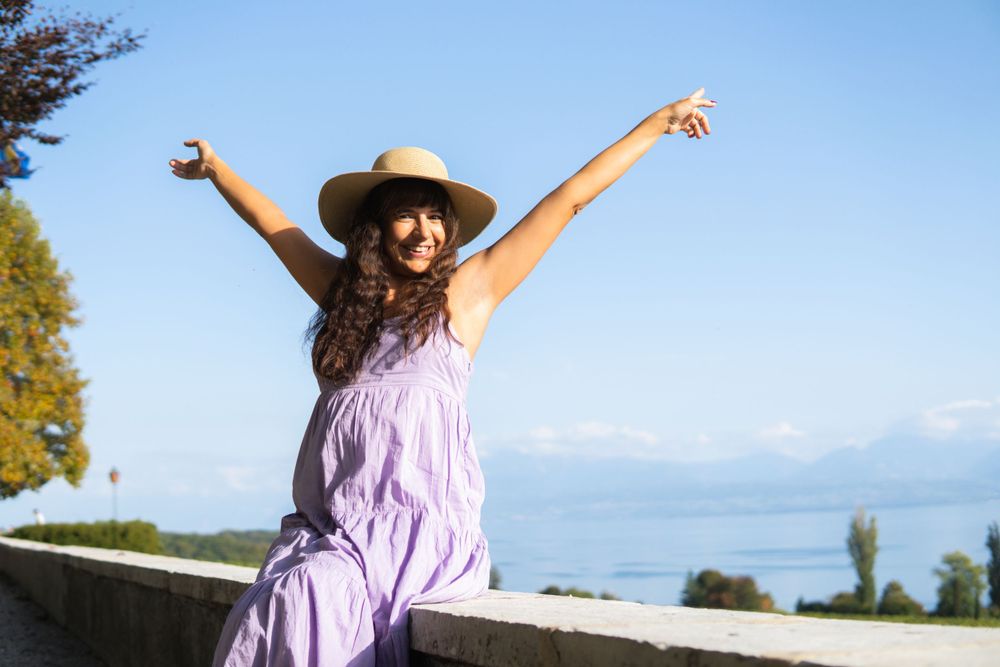A pregnant woman is sitting on the terrace, stretching her arms wide.