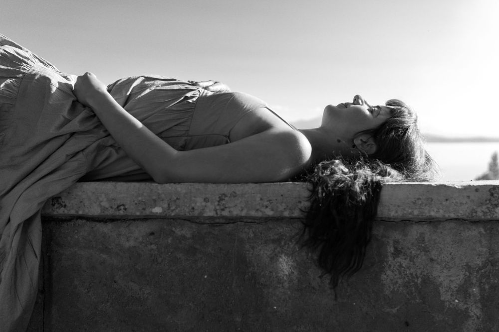 A pregnant woman is lying on the bench.