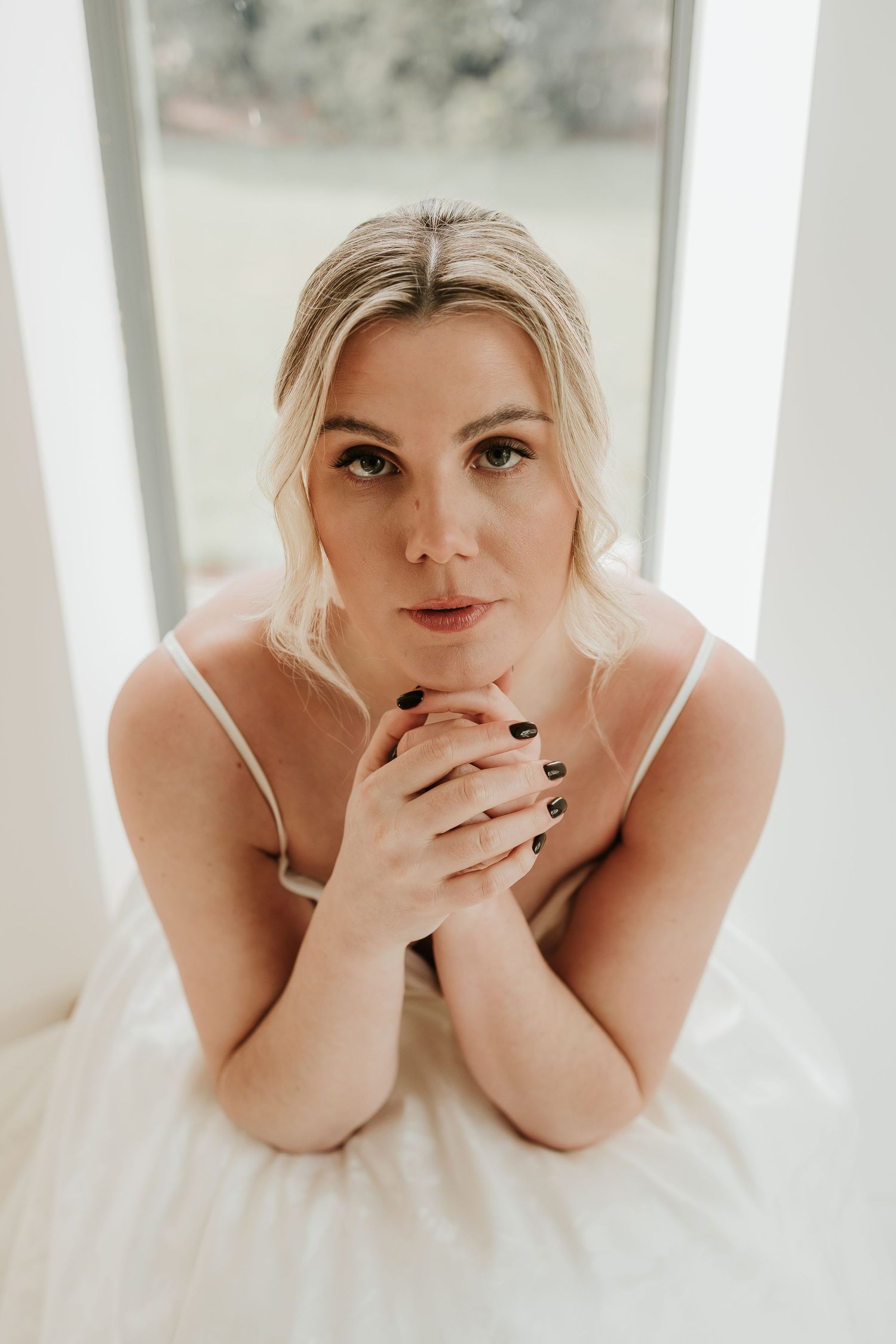Portrait in white dress against window.
